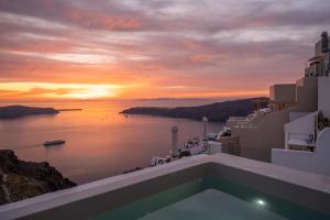 a sunset over the ocean with a swimming pool at Elia Cave Suites in Imerovigli