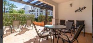 eine Terrasse mit einem Tisch und Stühlen auf einer Terrasse in der Unterkunft Bonito holiday, La Torre Golf Resort in Murcia
