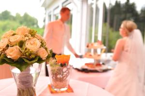 un hombre y una mujer de pie en una mesa con un jarrón de flores en Hotel Landhaus Berghof en Wenden