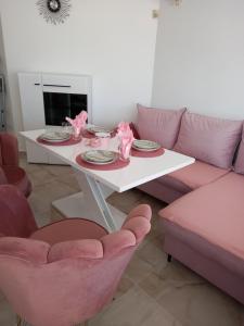 Perla 2 studio في مدينة بورغاس: غرفة معيشة مع طاولة بيضاء وكراسي وردية