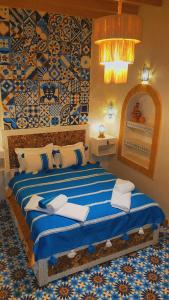 een slaapkamer met een bed met blauwe en witte lakens bij Riad Milal in Essaouira