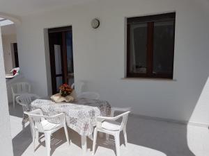 a table with white chairs and a vase of flowers on it at Gallipoli Mancaversa Futura Vacanza Andrea in Marina di Mancaversa