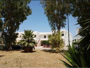 a white house with a palm tree in front of it at Gallipoli Mancaversa Futura Vacanza Andrea in Marina di Mancaversa