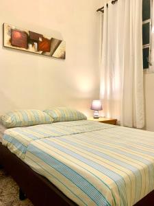 1 dormitorio con 1 cama con edredón de rayas azules en Suíte 300 Pitangueiras - na quadra da praia, en Guarujá