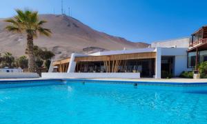 a swimming pool in front of a building with a mountain at Hotel Arica in Arica