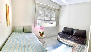 uma sala de estar com uma cama e um sofá em Pitangueiras Guarujá Apto com garagem no Guarujá