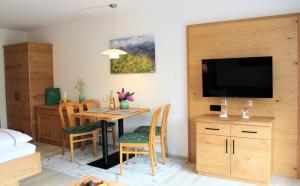 a room with a table and chairs and a television at Ferienwohnung Bergflora in Oberstdorf