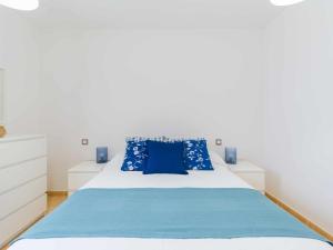 a bedroom with a white bed with blue pillows at Mahostly La Casita de mi Rosita in Puerto del Rosario