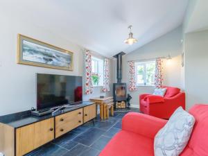 Golden Slack Cottage في Allgreave: غرفة معيشة مع كرسيين احمر وتلفزيون كبير