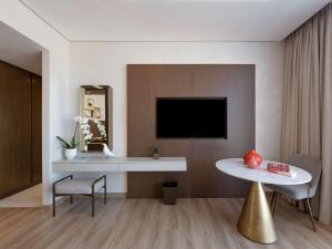 a living room with a tv and a table at Movenpick Jumeirah Village Triangle in Dubai