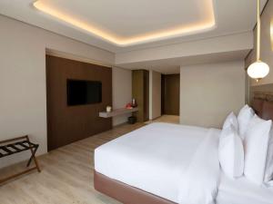 a bedroom with a white bed and a flat screen tv at Movenpick Jumeirah Village Triangle in Dubai
