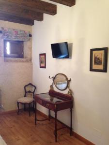 Habitación con mesa y TV en la pared. en Posada Real del Buen Camino, en Villanueva de Campeán