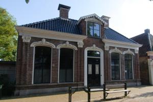 un edificio de ladrillo con un banco delante de él en Gastenverblijf De Oare Keamer Kollum Friesland, en Kollum