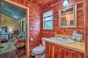 a bathroom with a toilet and a sink in a log cabin at Updated Studio Cabin in Ozark with Yard and Mtn View in Ozark