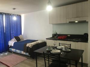 Habitación pequeña con cama, mesa y cocina en Apartment Relocation 1 Dormitorio, en Santiago