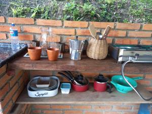 a counter with pots and pans on a brick wall at Chalé Floresta Toca da Serra in Iporanga