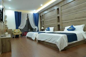 two beds in a bedroom with blue curtains at Huyen Nga Hotel in Buon Ma Thuot