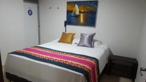 a bedroom with a bed with a painting on the wall at Hotel La Castellana in Manizales