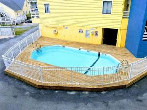 a large swimming pool with a deck and a yellow building at Beach Harbour 16 @ The Carolina Beach Boardwalk - Full Remodel! in Carolina Beach