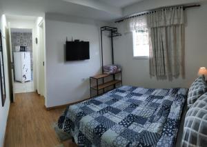 um quarto com uma cama e uma televisão na parede em Residencial Recanto Genebra - Campos do Jordão em Campos do Jordão