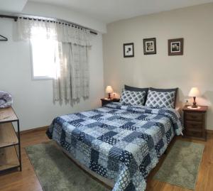um quarto com uma cama azul e branca e uma janela em Residencial Recanto Genebra - Campos do Jordão em Campos do Jordão