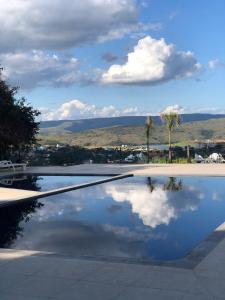 une piscine à reflet d'un nuage dans l'eau dans l'établissement Suíte no Mirante em Escarpas, à Capitólio