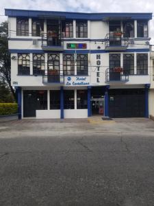 un edificio azul y blanco con aparcamiento en Hotel La Castellana, en Manizales