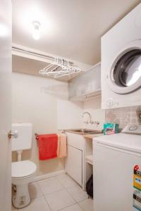 y baño pequeño con aseo y lavadora. en Upstairs Studio Apartment with street access en Melbourne