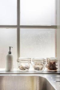 a window sill with jars and a bottle of soap at Upstairs Studio Apartment with street access in Melbourne