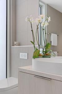 a bathroom with a vase with white flowers on a counter at Designer Luxury for 2 in Mornington