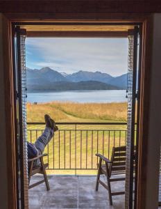 una persona sentada en una silla en un balcón con vistas en Fiordland Lodge en Te Anau