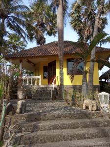 una casa amarilla con palmeras delante en Villa Arjuna, en Seraya