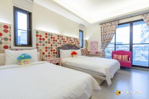 a bedroom with two beds and a chair and windows at Happiness is coming(Near Hualien Railway Station) in Hualien City