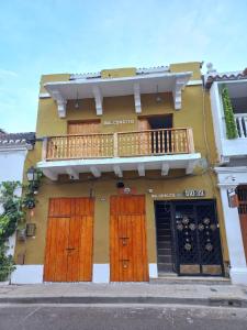 een geel gebouw met houten deuren en een balkon bij HOSTAL EL BALCONCITO in Cartagena