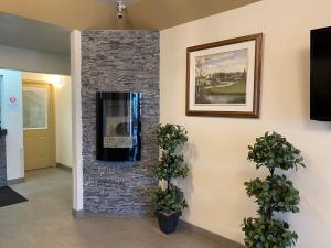 a stone fireplace in a hallway with two potted plants at Sleep Suite Motel in Steinbach