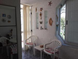 フォンターネ・ビアンケにあるVilla Mariaの白い椅子とテーブル、窓が備わる客室です。