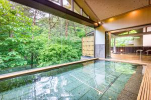 an indoor pool in a house with a view of the forest at Kashoen in Hanamaki