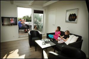 Volstrup Apartments في Stenild: مجموعة من الناس يجلسون على أريكة في غرفة المعيشة