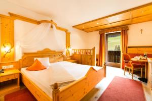 a bedroom with a bed and a table and a window at Berghotel in Racines