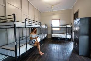 a woman sitting on a bed in a room with bunk beds at The Jack Backpackers in Cairns