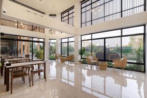 a large room with tables and chairs and windows at The Pride Hotel Phitsanulok in Phitsanulok