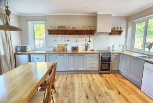cocina con armarios blancos y mesa de madera en South Lodge, Glenfintaig, en Spean Bridge