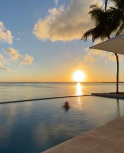 una persona en una piscina con una puesta de sol en el océano en Casa Tortugas Boutique Hotel - CANCUN Hidden Gem en Cancún