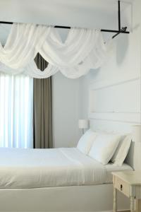 a bedroom with a white bed with white drapes at Harmony Hotel in Sarandë