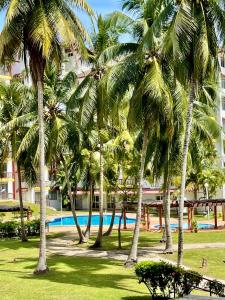 un grupo de palmeras en un parque con piscina en SEA LA VIE @ LAGUNA CONDO RESORT, en Port Dickson