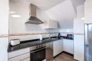cocina con armarios blancos y nevera de acero inoxidable en MA Maisons & Apartments Portonovo, en Portonovo