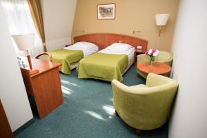 una habitación de hotel con 2 camas y una silla en Hotel Rezydencja Solei, en Poznan