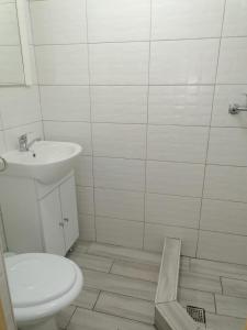 uma casa de banho branca com um lavatório e um WC em Emyra's holiday rooms em Constança