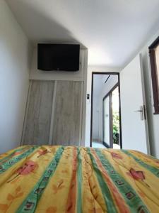 een slaapkamer met een bed en een flatscreen-tv bij Pavillon avec terrasse 6 personnes, piscine, 700m Plage 6EV2PAV425 in Saint Pierre La Mer