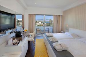 a hotel room with two beds and a flat screen tv at Nestor Hotel in Ayia Napa